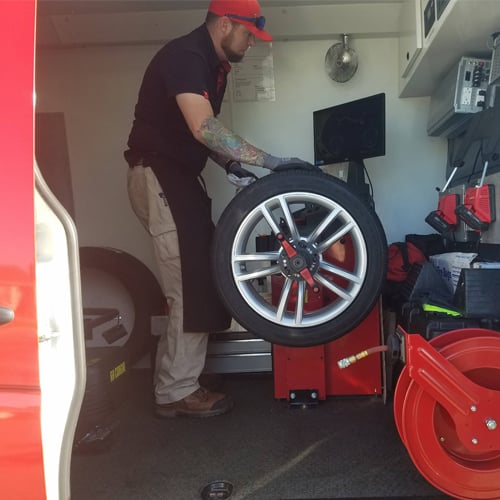 Truck technician setting a tire and wheel up on a balancing machine.
