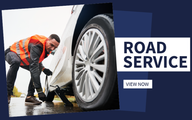A roadside assistance tech jacking up a vehicle that is on the side of the road.