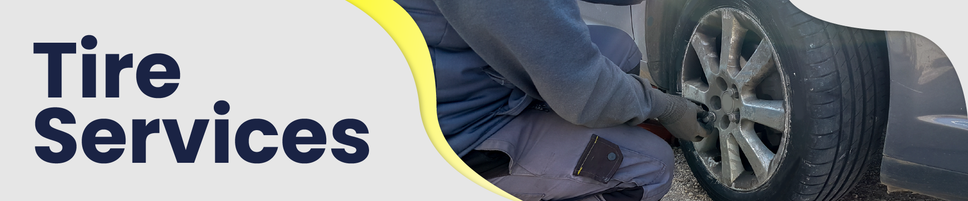 Technician leaning down to change a flat tire on an automobile.